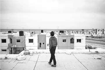  ??  ?? A boy walks on the roof of a damaged building in the Giza neighbourh­ood of Sirte.