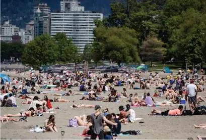  ?? DARRYL DYCK THE CANADIAN PRESS ?? People sun themselves at Kitsilano Beach in Vancouver on Saturday, as temperatur­es reached into the 20s.