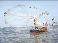  ?? NATALIJA GORMALOVA/AFP ?? A fisherman casts his net in the waters of the Gulf of Guinea, outside Jamestown, the oldest fishing community in Accra.