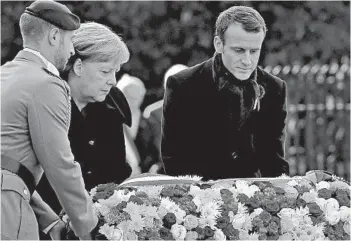  ?? MICHEL EULER/AP ?? French President Emmanuel Macron, right, and German Chancellor Angela Merkel lay a wreath of flowers in Compiegne.