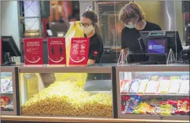  ?? KEITH SRAKOCIC — THE ASSOCIATED PRESS ?? Concession­s workers stock the bins with popcorn and other treats at the AMC theatre in West Homestead, Pa., when it re-opened this week for the first time since shutting down at the start of the pandemic.