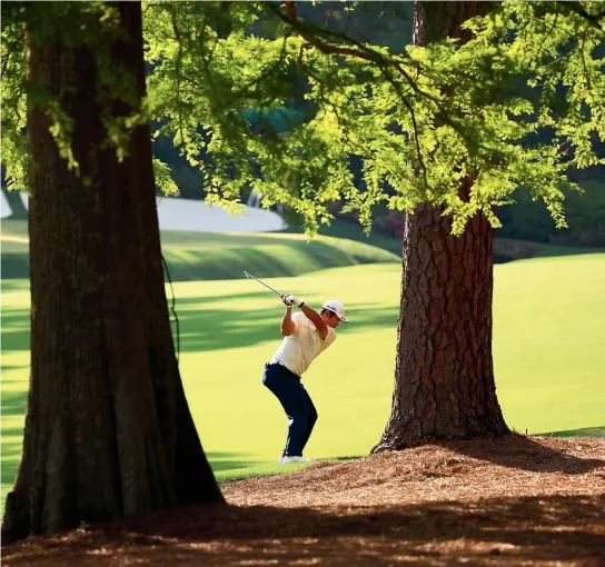  ?? GETTY IMAGES/AP ?? Japan’s Hideki Matsuyama plays his approach shot to the treacherou­s 13th green at Augusta National. Inset: Matsuyama and his caddie, Shota Hayafuji, admire the winner’s trophy at this year’s Masters.