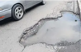  ??  ?? A motorist dodges a pothole along Marcus Garvey Drive.