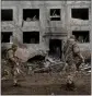  ?? LYNSEY ADDARIO THE NEW YORK TIMES ?? Ukrainian soldiers walk past a crater in front of a highrise building on Sunday, a day after a missile attack in Druzhkivka, Ukraine.