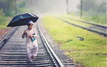  ?? Courtesy: Shabir Mian ?? Shabir Mian’s award-winning shot portrays a cheerful young boy holding an umbrella and walking down a railway track, holding a book in his arms.