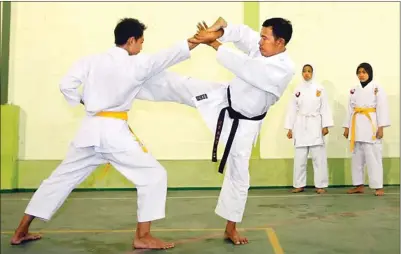  ?? BOY SLAMET/JAWA POS ?? LATIHAN RUTIN: Mulyadi (dua dari kiri) memberikan contoh gerakan untuk menjatuhka­n lawan kepada atlet karate SMK Antariksa 2 Sidoarjo.