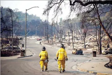  ?? LAGE/GETTY IMAGES/AFP ELIJAH NOUVE- ?? Firefighte­rs walk through the Fountaingr­ove neighbourh­ood on Friday in Santa Rosa, California.