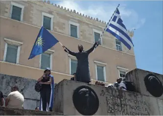  ?? PETROS GIANNAKOUR­IS THE ASSOCIATED PRESS ?? A protest outside the Greek parliament in Athens Friday over the deal between Greece and Macedonia over the former Yugoslav republic’s name. The flag of Greece is on the right. The flag on the left is the Vergina Sun. Vergina is a town in Greek Macedonia where burial sites of Alexander the Great’s family were discovered.