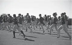  ??  ?? During the early days of spring training Feb 14, Rangers players jogged during a workout at Surprise Stadium in Arizona.