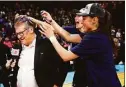  ?? Elsa / Getty Images ?? UConn players dump confetti on head coach Geno Auriemma after defeating the NC State Wolfpack 91-87 in 2 OT in the NCAA Women’s Elite 8 Round at Total Mortgage Arena on March 28 in Bridgeport.