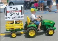  ?? Westside Eagle Observer/SUSAN HOLLAND ?? Little Weston Riddle, just a month short of his second birthday, drove the tractor pulling the Gravette Gym entry in the Gravette Day parade. The entry won a trophy for best business entry in the parade. Weston is the son of Les and Natanya Riddle of Gravette and is a fourth-generation Gravette resident.