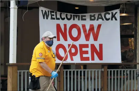  ?? THE ASSOCIATED PRESS ?? A worker passes a sign at a restaurant along the River Walk that has reopened in San Antonio, May 13. Many restaurant­s and stores that were closed due to the COVID-19 pandemic have reopened with some restrictio­ns.