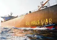  ?? Frank Molter / Associated Press ?? Greenpeace activists paint “oil fuels war” on the hull of a ship carrying Russian oil near Germany.