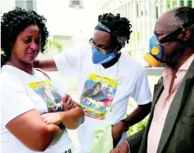  ?? GLADSTONE TAYLOR ?? Yanike Crosdale (left), mother of the late Jevaughn Duhaney, is consoled by Leon Duncan (centre) as they wait for Duhaney’s autopsy to be done at the House of Tranquilli­ty Funeral Home in Kingston yesterday. Looking on is Dr Jephthah Ford.