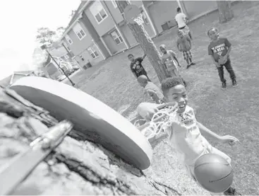  ?? Yi-Chin Lee / Houston Chronicle ?? Oxford Place Apartments resident Jerrell Llorance, 8, dunks a basketball into a newly installed goal. The public housing community gathered Saturday to celebrate the opening of a new, unique play space.