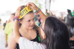  ?? MARIE D. DE JESUS/HOUSTON CHRONICLE ?? Diona Evans, right, helps her friend Sara Reul wear a headband at a high school class of 2008 reunion fundraisin­g event Sunday in Santa Fe, Texas, benefiting victims of the school shooting.