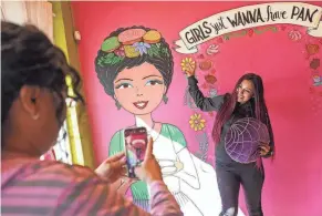  ?? ?? Ana Crawford, left, takes a photo of Sahray Uribe, at right, posing in front of a mural at Tres Leches Cafe on Oct. 29 in Phoenix.