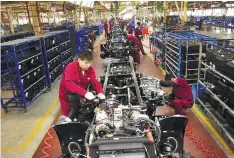  ??  ?? Workers installing chassis on a production line in a truck factory in Hefei, Anhui province. China’s factory output growth in June weakened to a two-year low.