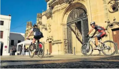  ?? RAMÓN AGUILAR ?? Dos ciclistas paseando este puente por la Plaza del Cabildo, junto a la iglesia de Santa María, en Arcos.