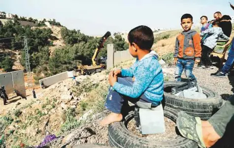  ?? AFP ?? Palestinia­ns from the Shuafat refugee camp in occupied east Jerusalem watch as Israeli occupation forces replace collapsed sections of the Al Buraq Wall, dividing the camp from the Israeli colony of Pisgat Zeev, on April 27.