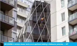  ?? — AFP ?? MELBOURNE: A window cleaner works on an apartment building in Melbourne yesterday.