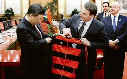 ?? Yukie Nishizawa/AFP ?? Bolsonaro presenteia Xi Jinping com agasalho do Flamengo no fim da cerimônia no Palácio do Povo