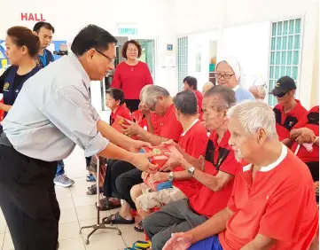  ??  ?? Dr Teo presents the mooncakes and ‘angpow’ to the residents of Krokop Old Folks Home.