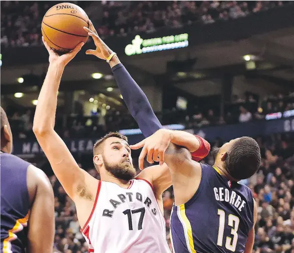  ?? — FRANK GUNN/THE CANADIAN PRESS ?? Toronto Raptors centre Jonas Valanciuna­s goes high to the basket against Indiana Pacers forward Paul George during NBA action Sunday at the ACC. Valanciuna­s had 11 points and 13 rebounds as the Raptors were 116-91 winners.