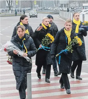  ?? EFREM LUKATSKY THE ASSOCIATED PRESS ?? A crew of a Ukrainian airline carries flowers to pay tribute to the flight crew members of the Ukrainian 737-800 plane that crashed on the outskirts of Tehran.