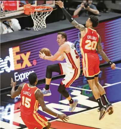  ?? AL DIAZ adiaz@miamiheral­d.com ?? Heat’s Duncan Robinson looks to pass from under the basket as the Hawks’ John Collins makes sure he has no room to shoot. Robinson tied for a team-high 14 points with Goran Dragic on a cold night for the Miami offense.