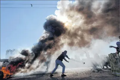  ?? AP PHOTO ?? Palestinia­n protesters burn tires and clash with Israeli troops following protests against U.S. President Donald Trump’s decision to recognize Jerusalem as the capital of Israel, in the West Bank city of Ramallah Friday.