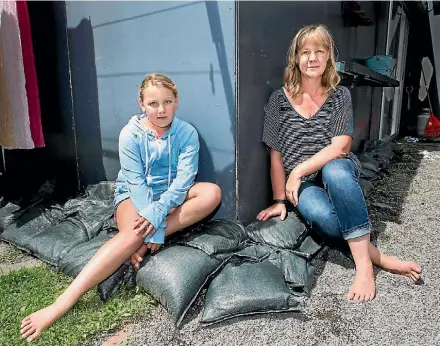  ?? PHOTO: MAARTEN HOLL/FAIRFAX NZ ?? Tanja Gerritsen and daughter Kate Osborne, 9, sit on sandbags in her backyard.