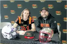  ?? BERND FRANKE/POSTMEDIA NETWORK ?? A.N. Myer Secondary School student athlete Tyler Scholz signs a letter of intent to play university football with the Guelph Gryphons while Gryphons defensive co-ordinator Doug Grandy looks on.