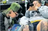  ?? AFP ?? Wang Qi (right) takes photos as she gets inked at a tattoo studio in Shanghai.
