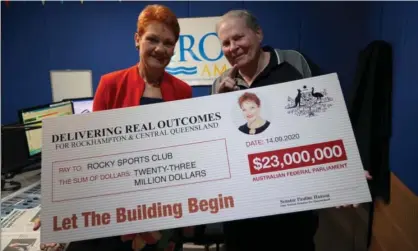  ?? Photograph: Pauline Hanson Please Explain Facebook ?? One Nation leader Pauline Hanson (left) poses with a $23m novelty cheque to announce a new 16,000-seat stadium in Rockhampto­n. Labor has asked the auditor general to investigat­e.