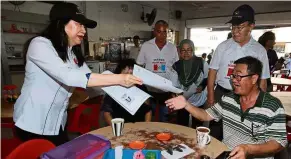  ??  ?? Spreading the word: Tsen distributi­ng leaflets to voters at an eatery in Sandakan.