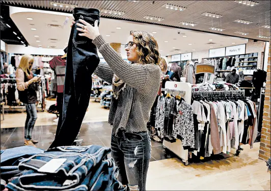  ?? SUZANNE TENNANT/POST-TRIBUNE PHOTOS ?? Employee Ashley Gidley folds jeans at The Buckle store inside the Southlake Mall.