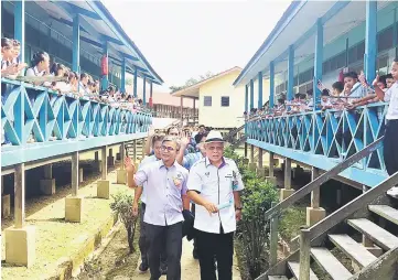  ??  ?? Manyin (right) and Dr Annuar being given a rousing farewell by the pupils of SK Nanga Selangau as they leave the school after a walkabout.