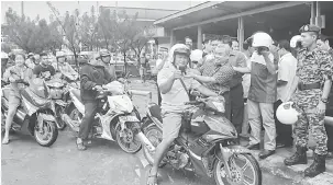  ??  ?? NITIHKA UNDANG-UNDANG: Belayong Pok nangkupka helmet ngagai siku orang ti mai mutosikal rambau Kimpin Pengelikun Jalai Bagi Menua Kapit.