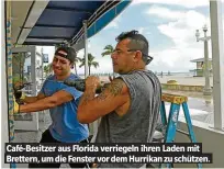  ??  ?? CAfé-Besitzer Aus FloridA verriegeln ihren LAden mit Brettern, um die Fenster vor dem HurrikAn zu sChützen.