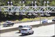  ?? Elise Amendola / AP Photo ?? Cars pass under a toll-sensor gantry hanging over the Massachuse­tts Turnpike. A transporta­tion group advising Gov.-elect Ned Lamont recommends installing electronic highways tolls as soon as possible.