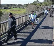  ??  ?? Phil Mickelson walks across the fifth-hole bridge on Sunday. The popular player is gunning to join Mark O’Meara as a five-time winner of the tournament.