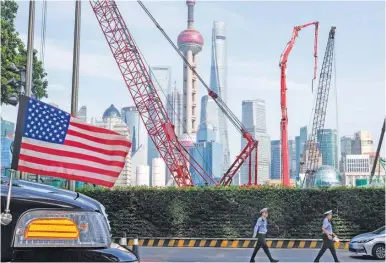  ?? AP/NG HAN GUAN ?? Chinese traffic police officers walk by a US flag on an Embassy car outside a hotel in Shanghai.