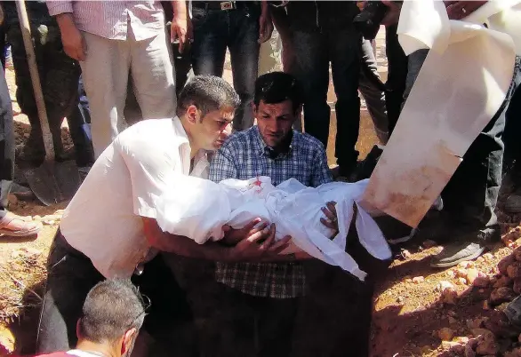  ?? AFP/GETTY IMAGES ?? Abdullah Kurdi, centre, holds the body of his son Alan, who drowned off the Turkish coast with his mother and brother. A funeral service was held Friday in Kobani, Syria.