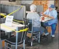  ?? Sue Ogrocki The Associated Press ?? George Kolokotron­ex, right, and his wife, Nancy Kolokotron­ex, left, eat lunch at Falcone’s Pizzeria in Oklahoma City on Friday, as restaurant­s are allowed to open for inperson dining. Tables are taped off to promote social distancing.