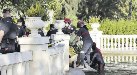  ??  ?? Momento en el que los bomberos sacan el cadáver del agua en presencia de los agentes de la Policía Local y la Policía Nacional, ayer por la tarde.