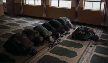  ?? (AP/Felipe Dana) ?? Taliban members lay their weapons down Sunday as they pray inside a mosque in Kabul, Afghanista­n.