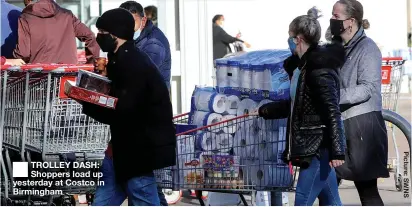  ??  ?? TROLLEY DASH: Shoppers load up yesterday at Costco in Birmingham