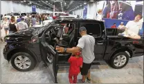  ?? LM OTERO / ASSOCIATED PRESS ?? Fairgoers look at a pickup on display at the State Fair of Texas in Dallas on Monday. Buyers are increasing­ly outfitting their pickups with all the comforts of luxury cars, from heated and cooled seats to backup cameras to panoramic glass roofs.