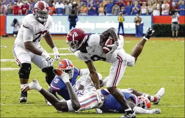  ?? PHOTOS BY JOHN RAOUX/ASSOCIATED PRESS ?? Alabama wide receiver John Metchie III hurtles past Florida defenders Saturday in Gainesvill­e, Florida. Alabama has won eight straight in the series, including a wild victory in last year’s conference title game.